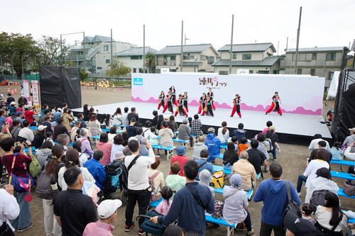練馬まつりの屋外ステージで踊るチームと、ベンチで見る観客