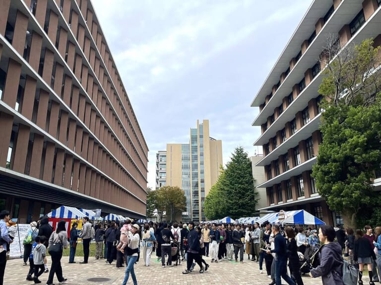 東京農業大学世田谷キャンパスの校舎の間に模擬店のテントが並び大勢の来場者が歩いている