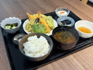 黒い盆に野菜とえびの天ぷら、ご飯、味噌汁、天つゆ、塩、きゅうりの小鉢、デザートが並んだみよしランチ
