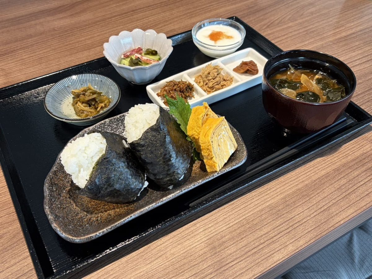 のりを巻いたおむすび2個と卵焼き、小鉢3品、味噌汁、デザートが盆にのったおむすびランチ
