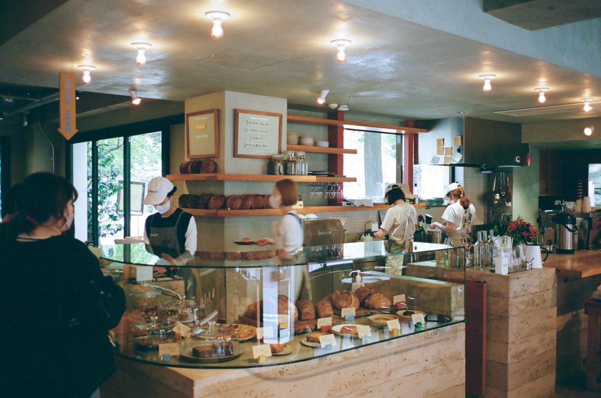 ガラスケースにパンが並び、スタッフがカウンターに立つベーカリーカフェの店内