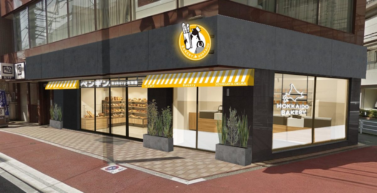 ペンギンベーカリー祖師ヶ谷大蔵店の外観イメージ。角地の黒い外壁の建物に黄色いひさしと「ペンギン」の看板