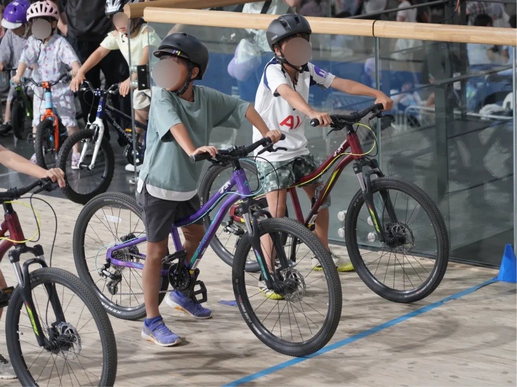 2026年7月のPIST6夏まつりの自転車タイムアタック。ヘルメットをかぶりバンクで出走を待つ子どもたち