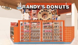 オレンジ色のショーケースにドーナツが並び、上部に大きなドーナツ型の看板とRANDY'S DONUTSのロゴがある売場の完成予想図