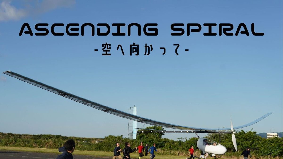 青空の下、滑走路で離陸する白い人力飛行機と、横を走って支える学生たち