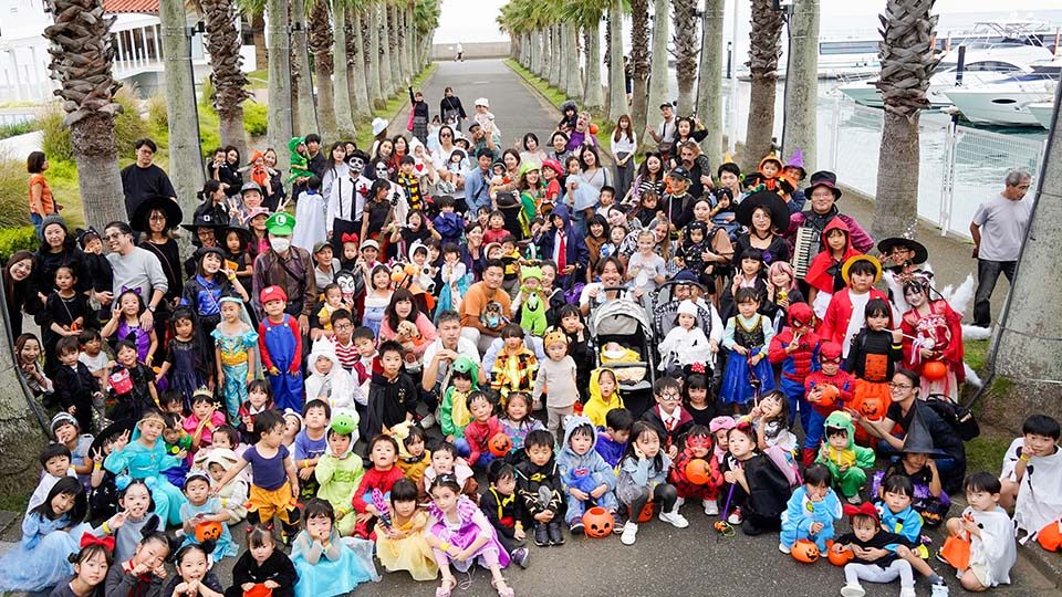 ヤシ並木の前で仮装した子どもたちと家族が集まった記念撮影