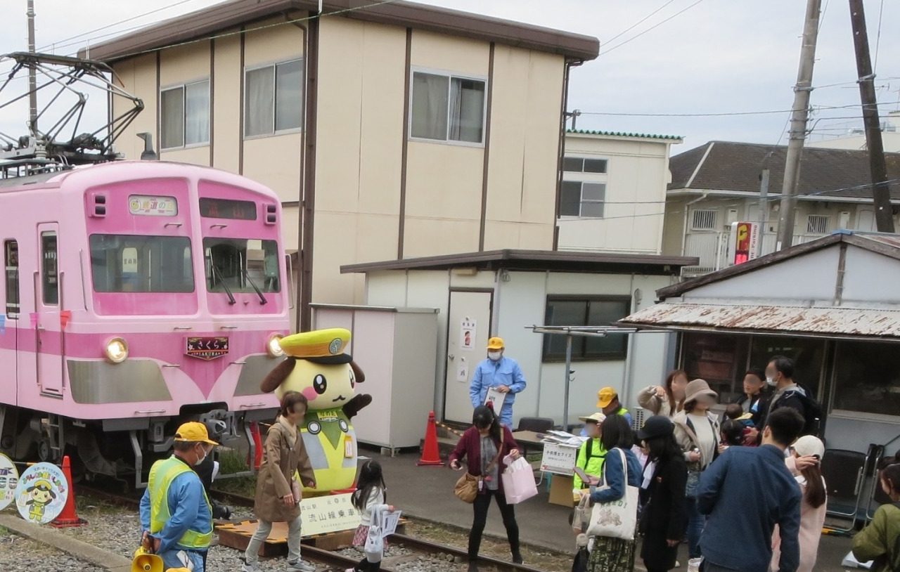 流山駅の構内で、ピンク色の流鉄の車両の前に立つキャラクター「りゅうのしん」と、集まった親子連れや係員