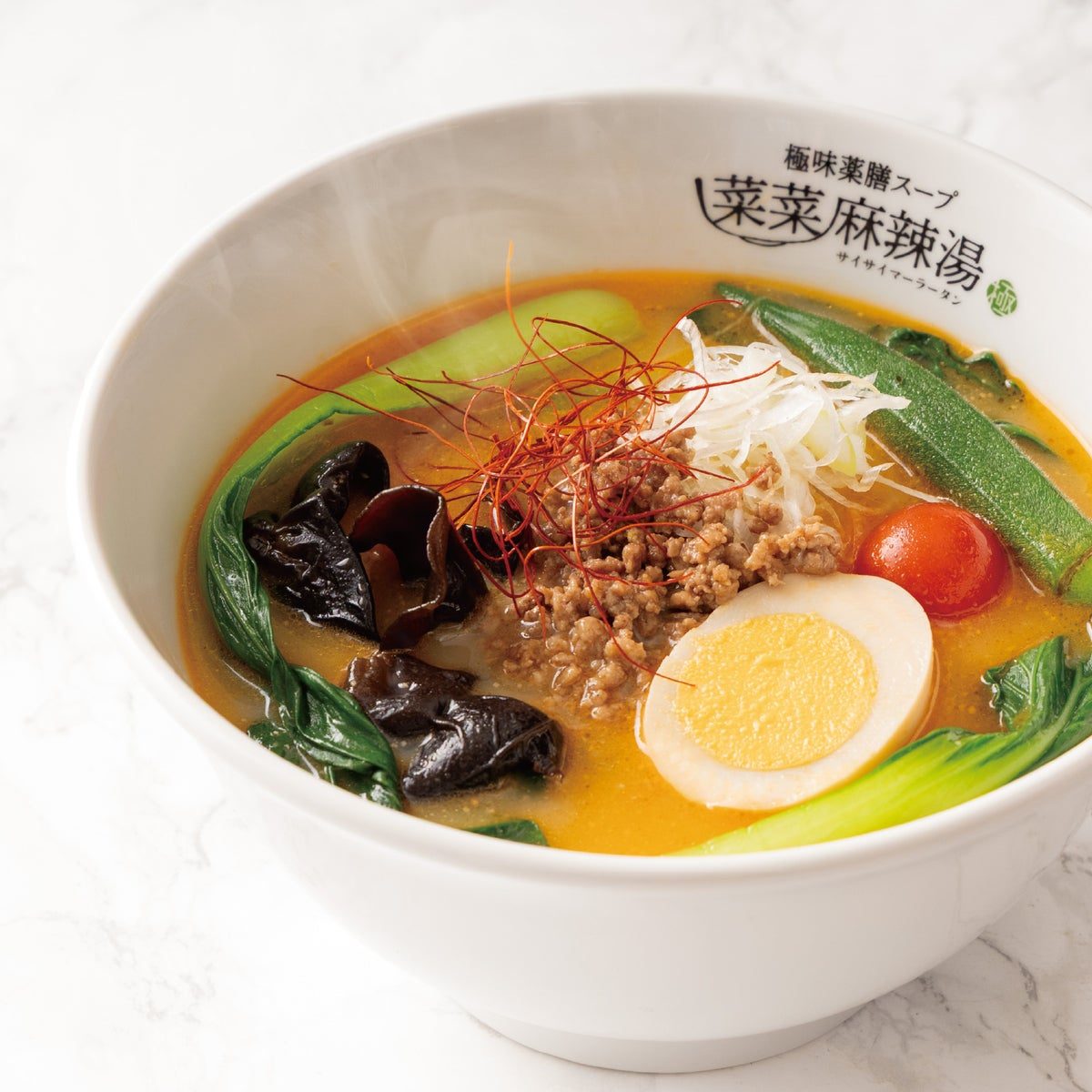 白い器に担々スープ、そぼろ、ゆで卵、キクラゲ、青菜、オクラ、糸唐辛子が入った麻辣湯