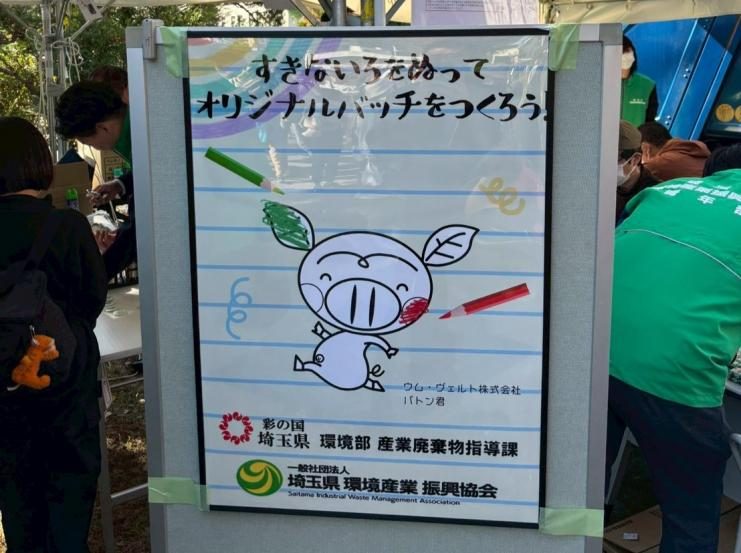 「すきないろをぬって オリジナルバッチをつくろう!」と書かれ、色鉛筆と葉っぱの耳のキャラクターの線画、埼玉県産業廃棄物指導課と埼玉県環境産業振興協会の名前が入ったパネル