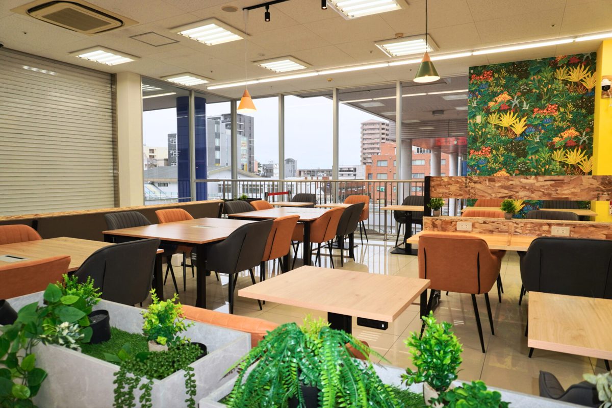 セルフカフェ フィールズ南柏店の窓側の席。ガラス越しに南柏駅前の建物が見え、テーブル席が並んでいる
