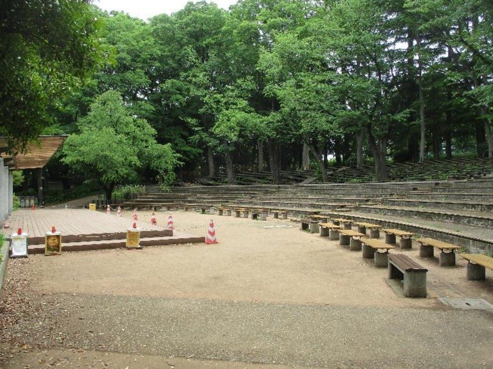 木立に囲まれた屋外の舞台と、その前に階段状に並ぶ客席とベンチ