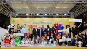 シタマチ.ハロウィンの仮装コンテスト表彰式。ステージ上に仮装した子どもや大人、パンダの着ぐるみが並び、賞状を掲げている