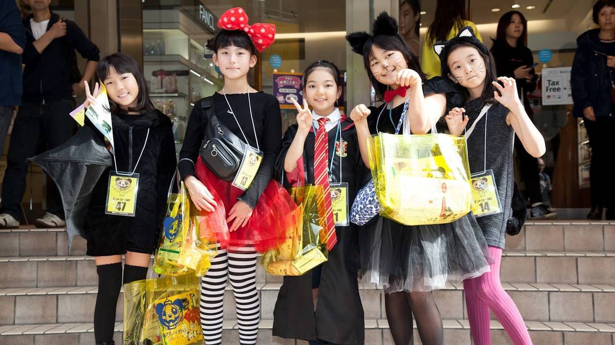 黒い仮装でお菓子の入った黄色いバッグを持つ子どもたちが階段の前で並ぶ写真