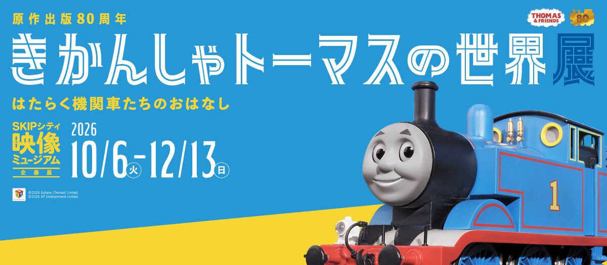 青と黄色の背景に「原作出版80周年 きかんしゃトーマスの世界展 はたらく機関車たちのおはなし」「SKIPシティ映像ミュージアム企画展 2026 10/6〜12/13」と書かれ、右にトーマスの模型が写る告知バナー