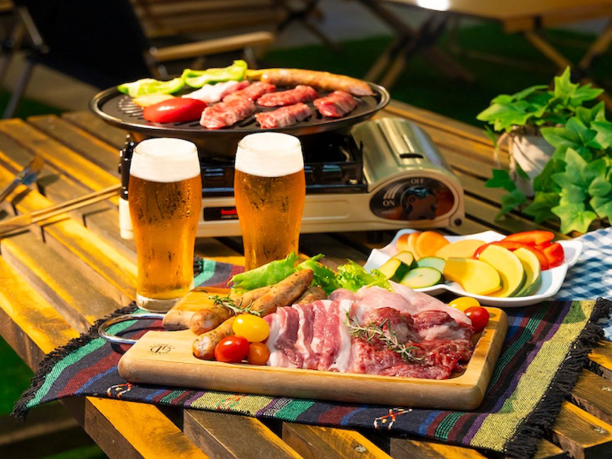 グリドルに載せた肉や野菜と、ジョッキのビールを並べたBBQの提供イメージ