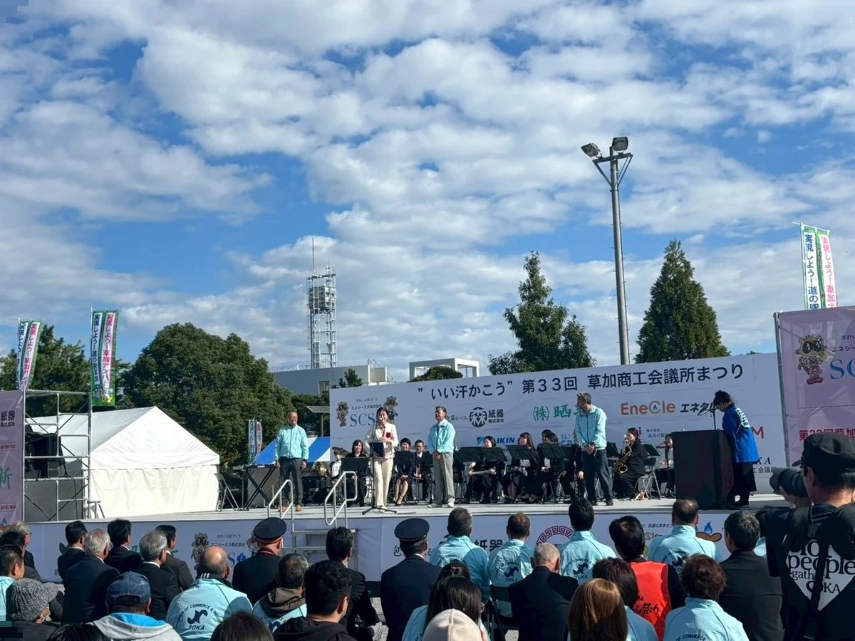 「いい汗かこう」第33回草加商工会議所まつりの看板が掛かったステージと観客