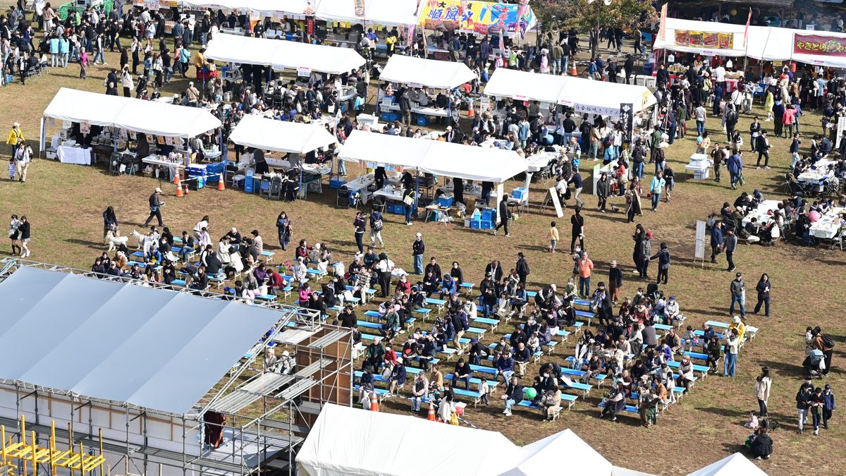 すぎなみフェスタ2025の桃井原っぱ公園。芝生広場に白いテントが並び、中央の飲食スペースに多くの来場者が座っている