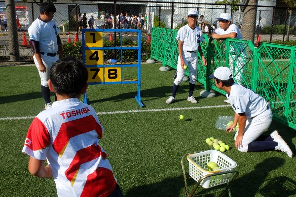 人工芝の野球場で子どもがストラックアウトにボールを投げる、こどもまつりのわんぱく広場