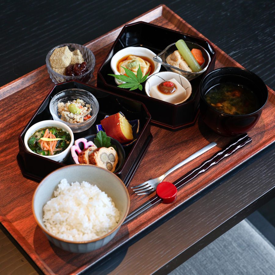 八角形の黒い重箱2段に胡麻豆腐や煮物、和え物などを盛り、ご飯と味噌汁、わらび餅を添えた精進料理の弁当