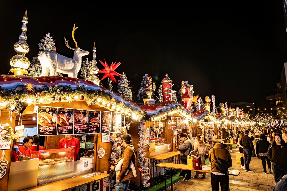 装飾されたヒュッテが並び、夜に多くの人が集まるクリスマスマーケット
