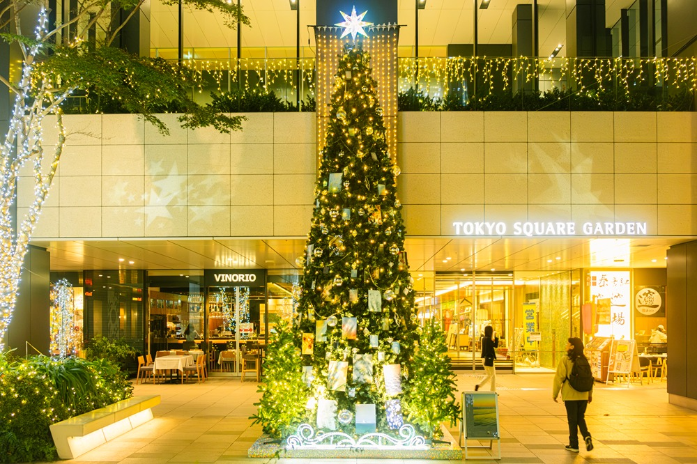 金色に光るツリーと、電球で飾られた植栽と建物の入口