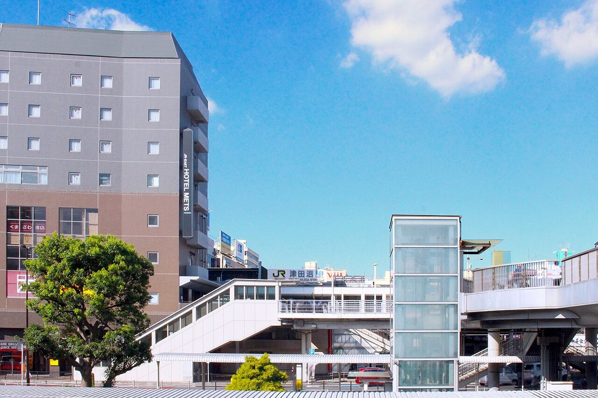 JR津田沼駅の南口。駅名看板のある橋上駅舎とペデストリアンデッキ、左にホテルメッツ