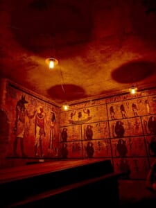 赤茶色の壁一面に古代エジプトの神々の壁画が描かれ、天井の電球が照らす玄室の再現展示