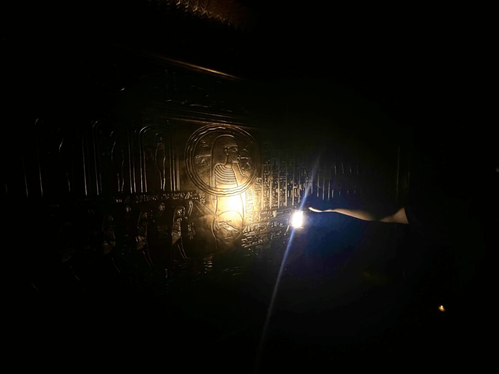 暗い館内で、金色の装飾が施された厨子がランタンの明かりに照らされている