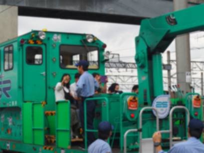 浦和美園車両基地で、緑色のモーターカーの運転台に子どもと大人が乗っている