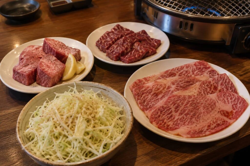 厚切りの牛タン塩とハラミ、大判のロース、千切りキャベツのサラダを並べた焼肉のイメージ画像