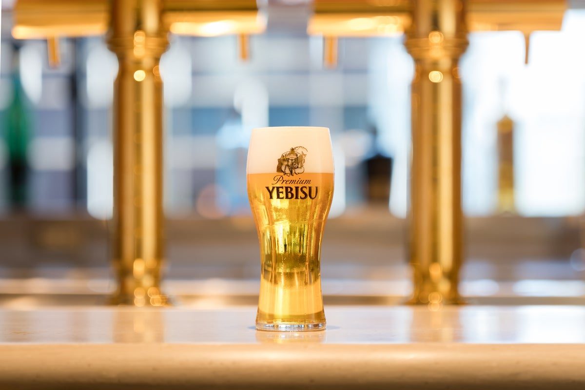 金色のビールサーバーの前のカウンターに、YEBISUのロゴ入りグラスに注がれたヱビスビールが置かれた写真