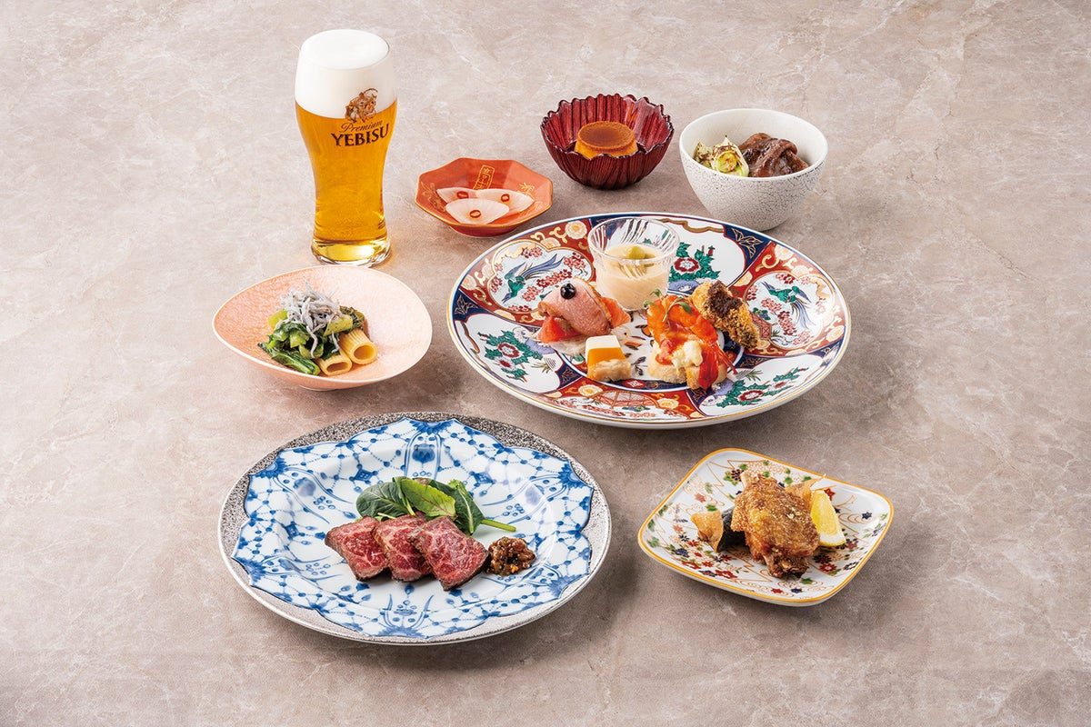 ヱビスビールのグラスと、和牛のステーキや前菜、焼き物を盛った複数の和柄の皿を並べた写真