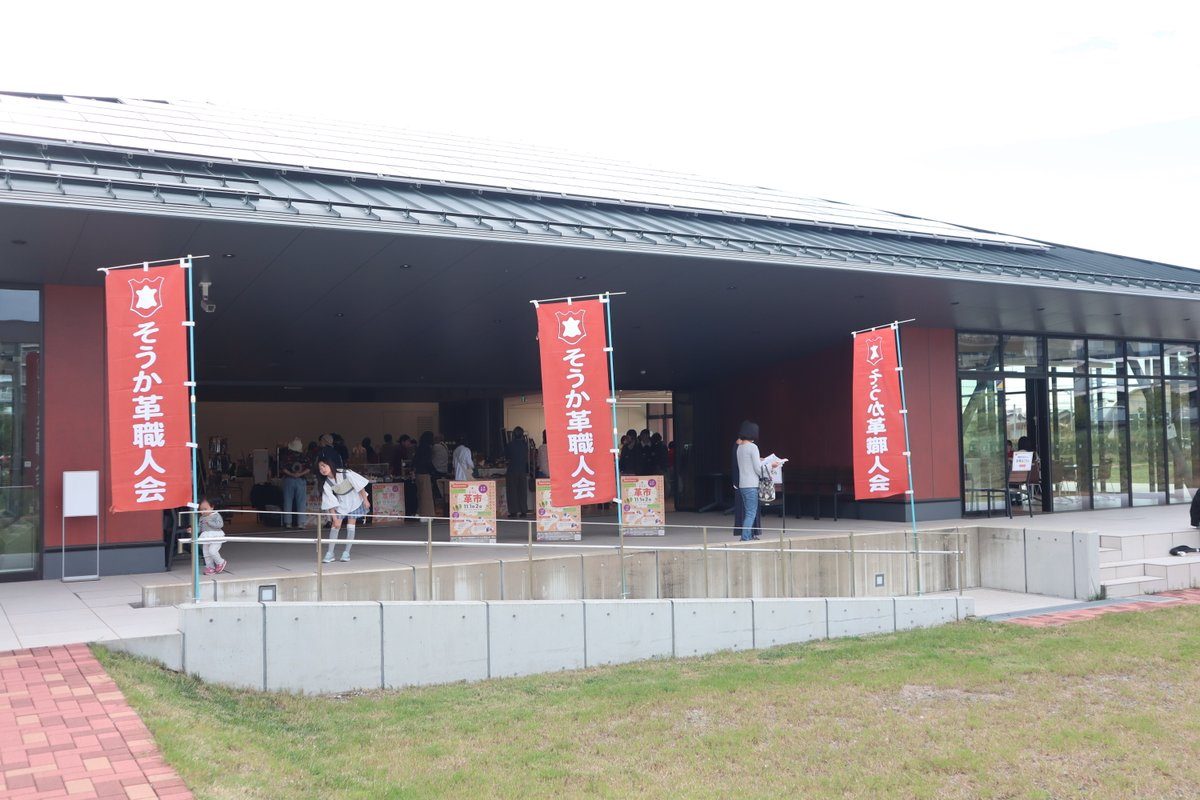 獨協大学コミュニティスクエアの建物の前に「そうか革職人会」ののぼりが立ち、中で革製品が売られている様子
